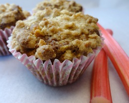 A photograph of some rhubarb and pumkin muffins with some rhubarb sticks on the side